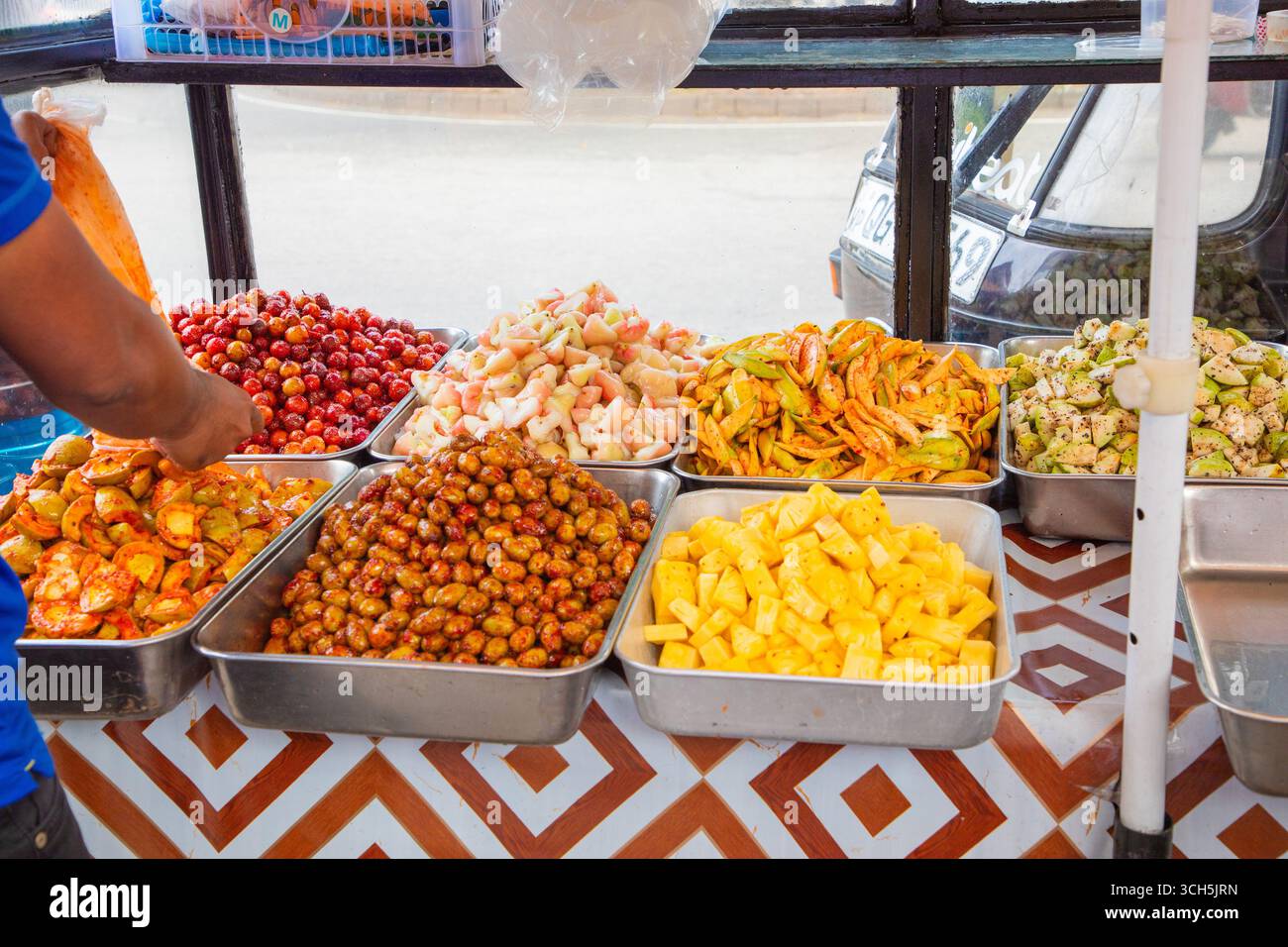 Verschiedene Street-Food-Optionen in der Hauptstadt Sri Lankas. Obst mit Gewürzen, gebratene Kuchen, Salate. Überfüllte Straßen des Pettah Market in Colombo Stockfoto