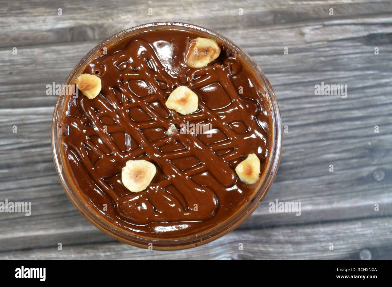 Schokoladencreme mit Kuchen, gekrönt mit Schokoladenpaste und Haselnussstücken und mit Kuchen überzogen, ein weiches, zubereitetes Essen mit Schichten geschlagener Crea Stockfoto