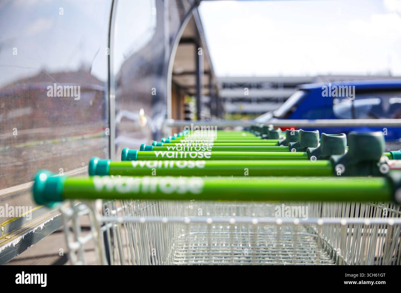 Reihe von Einkaufswagen für den Waitrose-Supermarkt mit grünem Griff im Outdoor-Trolley-Park, Großbritannien Stockfoto