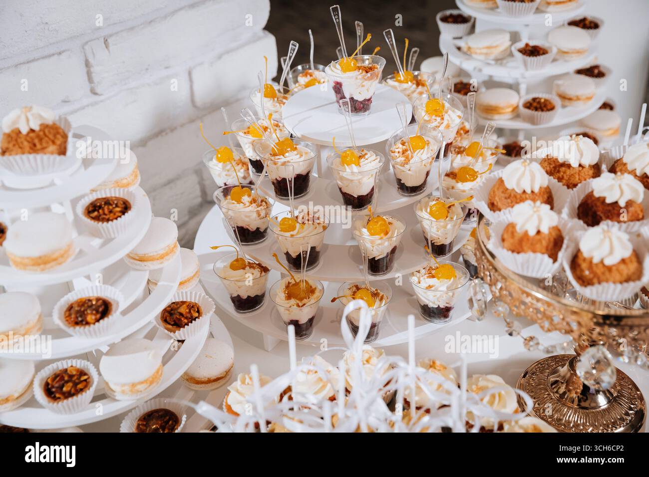 Luxuriöse Schokoriegel mit Cupcakes, Macarons und Desserts auf eleganten goldenen Tabletts Stockfoto