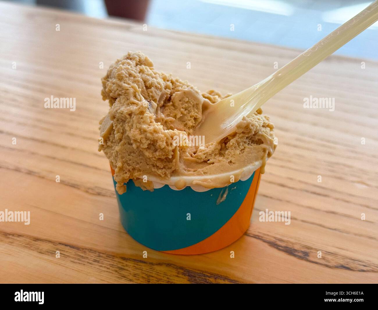 Portion Eis mit Kaffeegeschmack in einer Tasse. Kaltes Dessert mit Plastiklöffel Stockfoto
