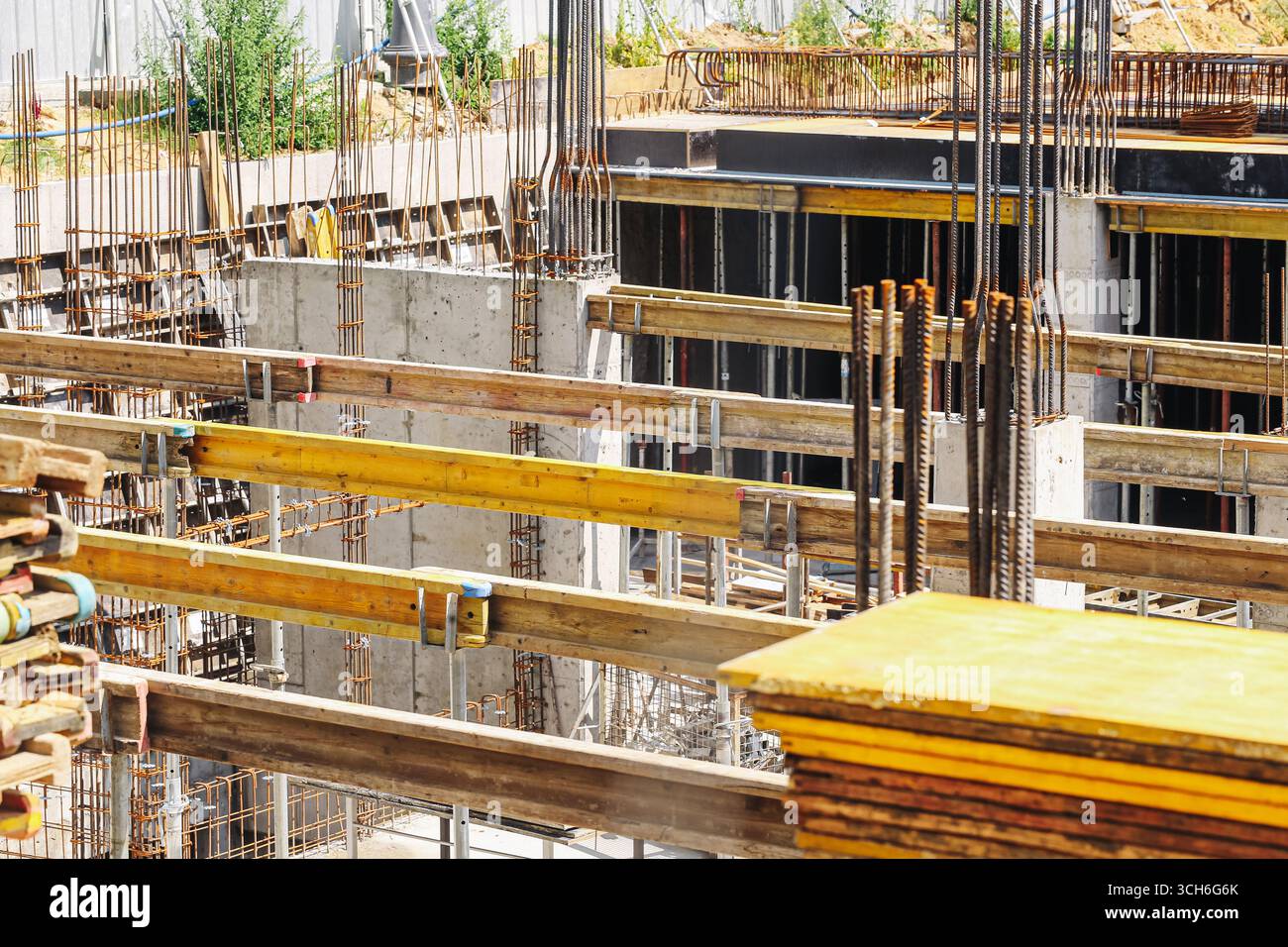 Betongebäude im Bau mit Stahlstangen. Industrielle Arbeiten im Gange. Details zum Architekturprojekt. Stadtentwicklung mit Plattformen Stockfoto