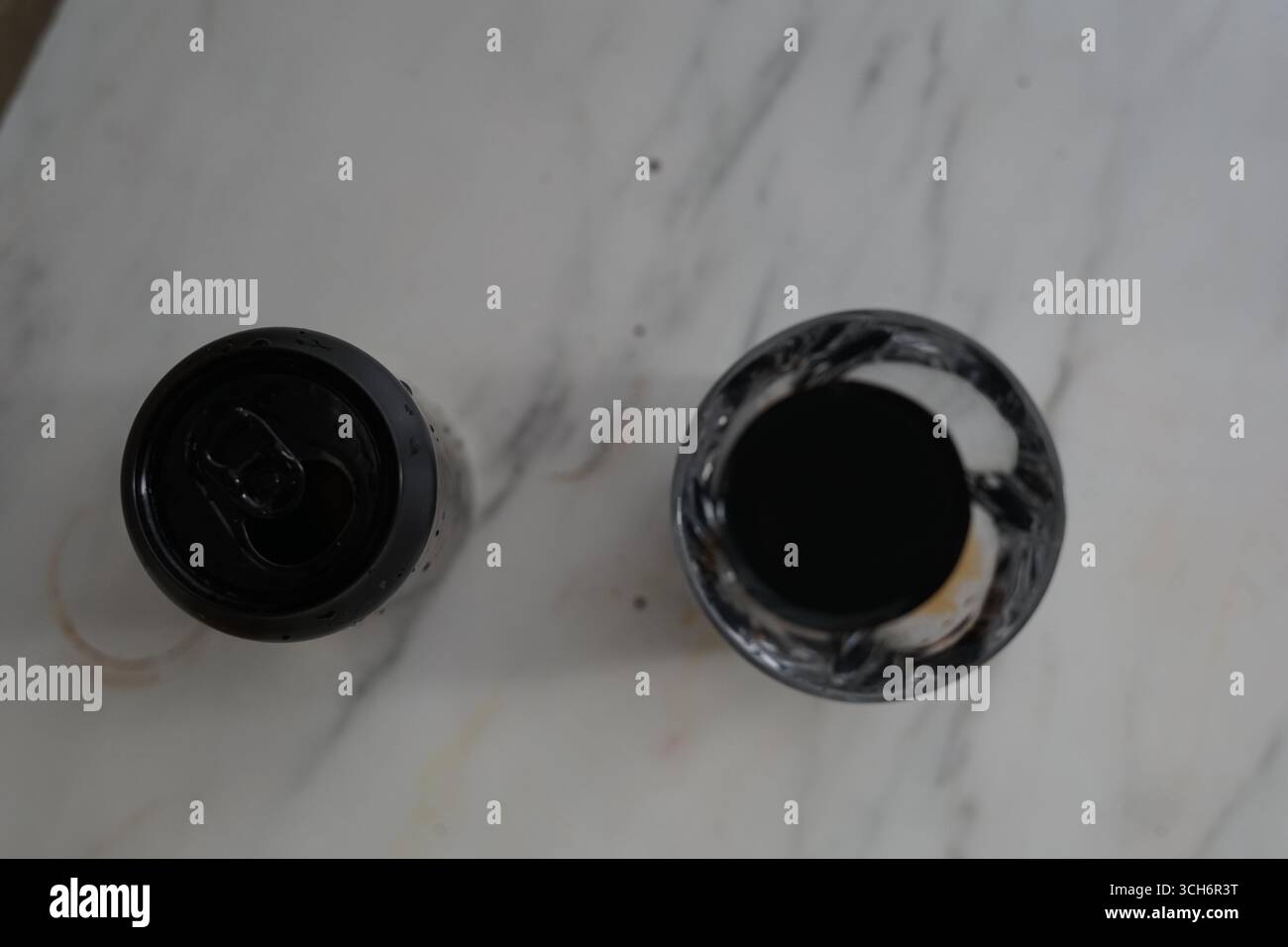 Eine optisch eindrucksvolle Anordnung von zwei einzigartigen Behältern, einer dunkel und der andere mit marmorfarbenem Muster, die auf einer glatten Marmoroberfläche stehen. Stockfoto