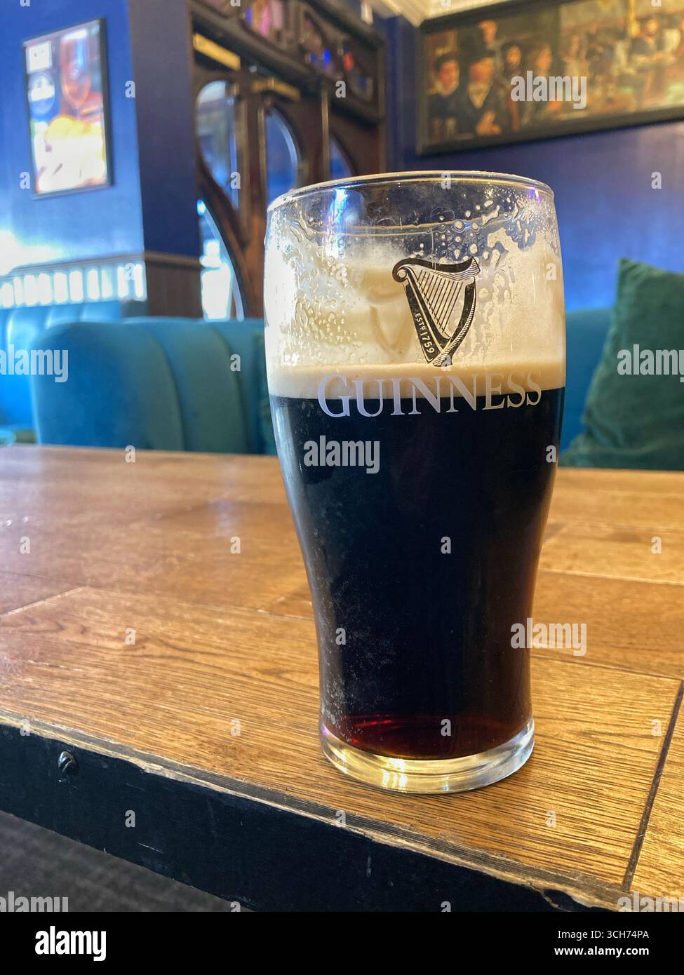 Das G mit einem Pint Guinness in einem traditionellen britischen Pub aufteilen - Smartphone-aufgenommenes Stockfoto