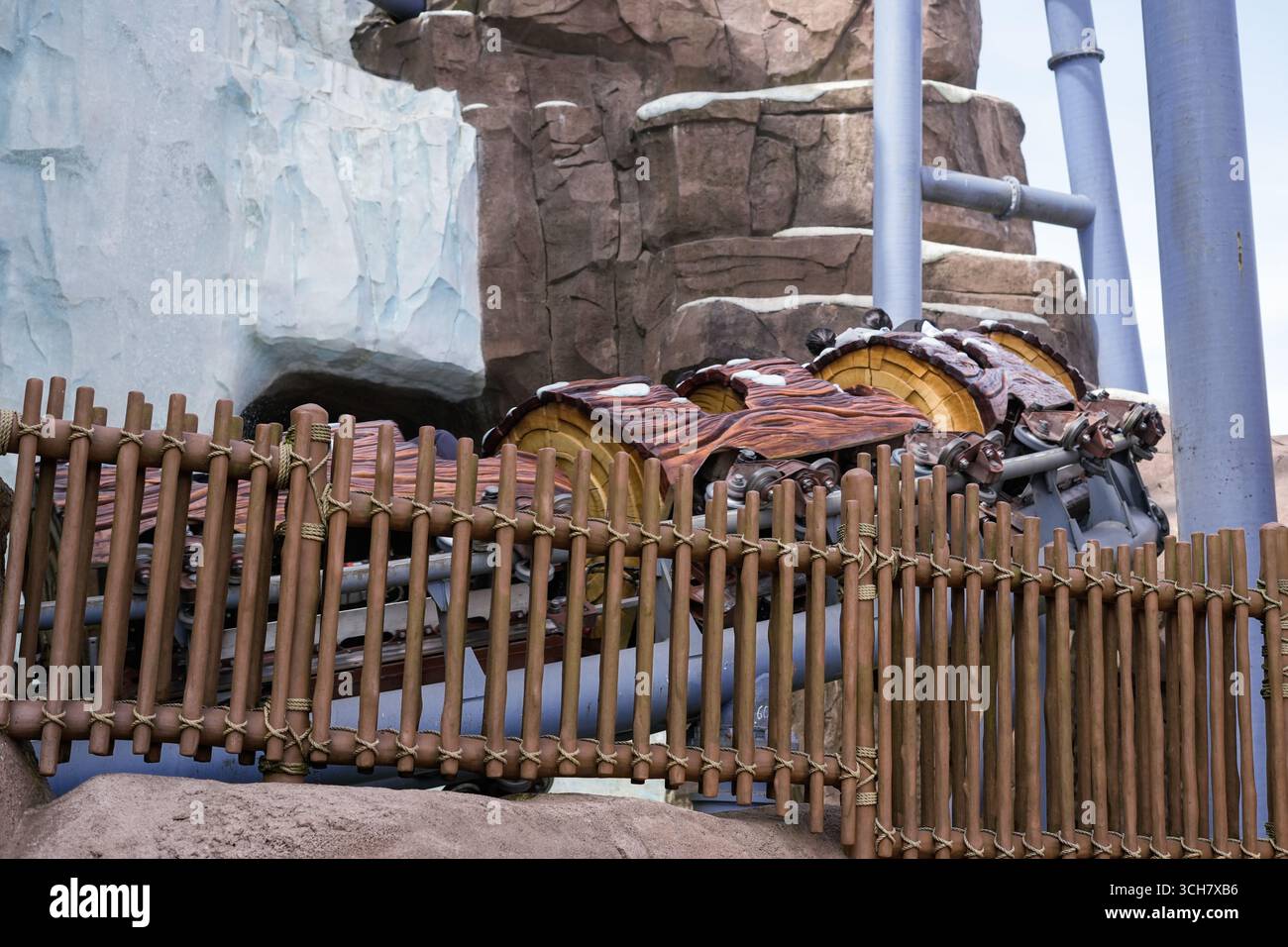 Eine Hochgeschwindigkeits-Achterbahn schlängelt sich entlang Stahlketten, während die Fahrer die Fahrt genießen Stockfoto