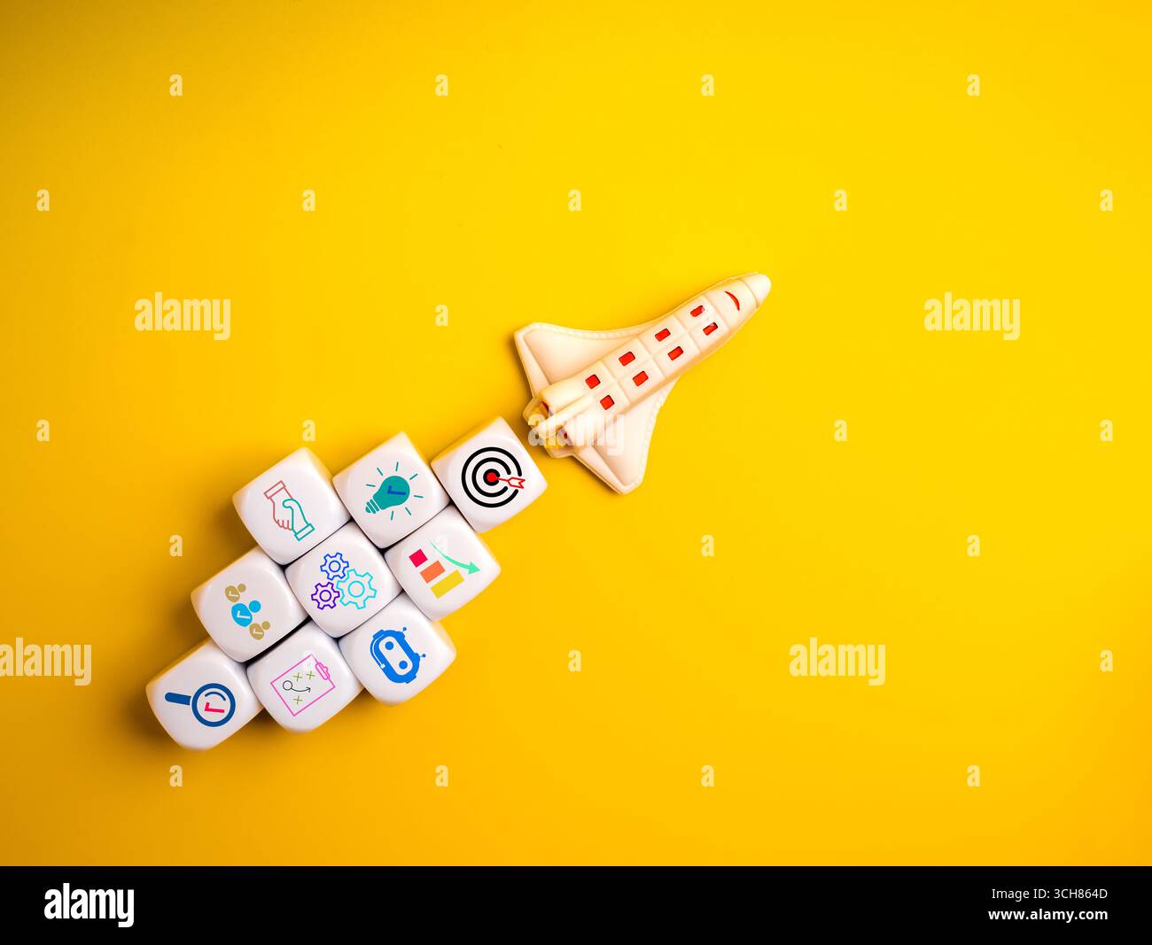 Kreative Rakete mit Startup-Symbolen auf weißen Würfeln auf gelbem Hintergrund symbolisiert Startup-Strategie, Unternehmenswachstum, Innovationsplanung und Unternehmertum Stockfoto