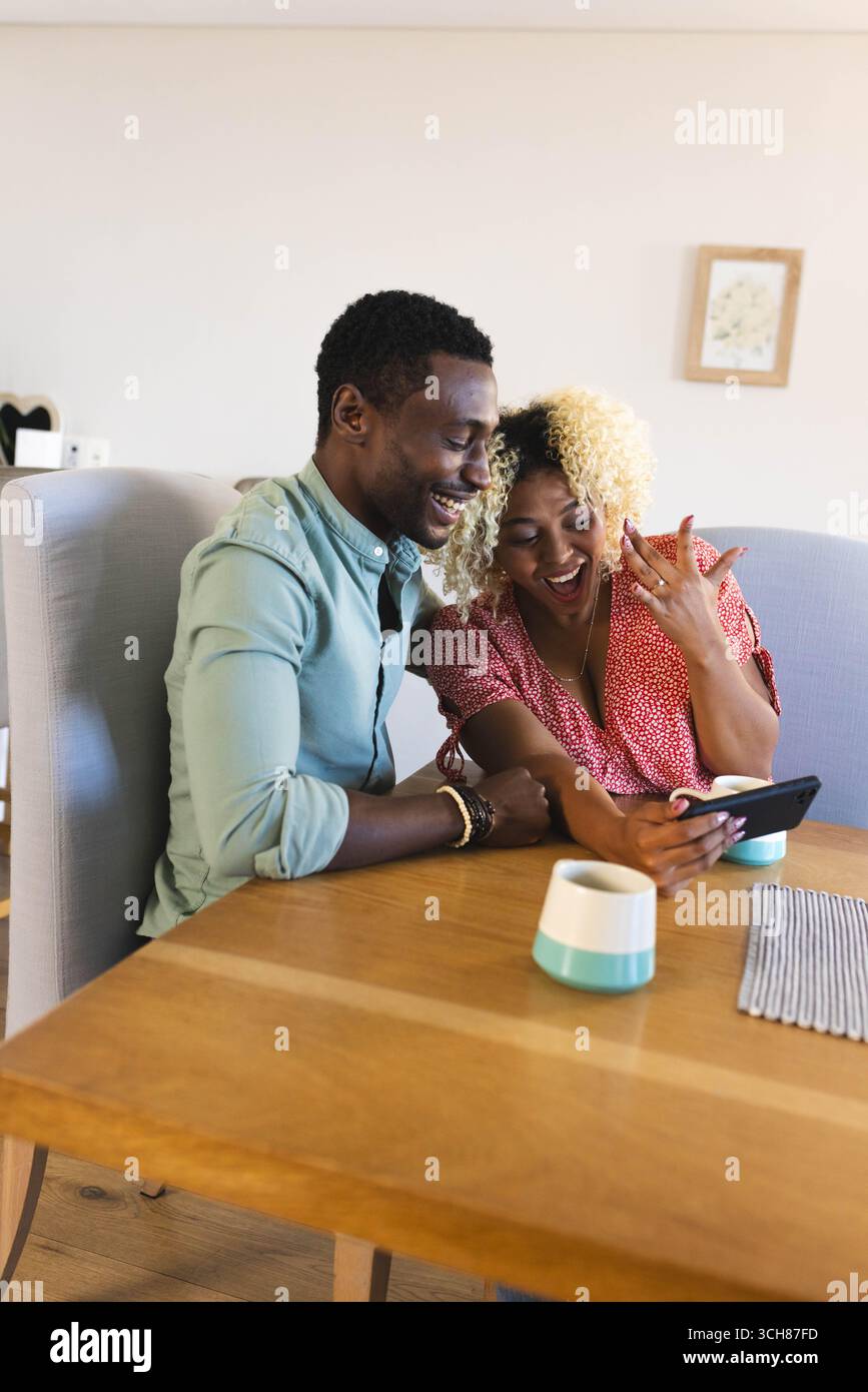 Freunde lachen zusammen, während sie etwas auf dem Smartphone am Esstisch und Kopierraum anschauen Stockfoto