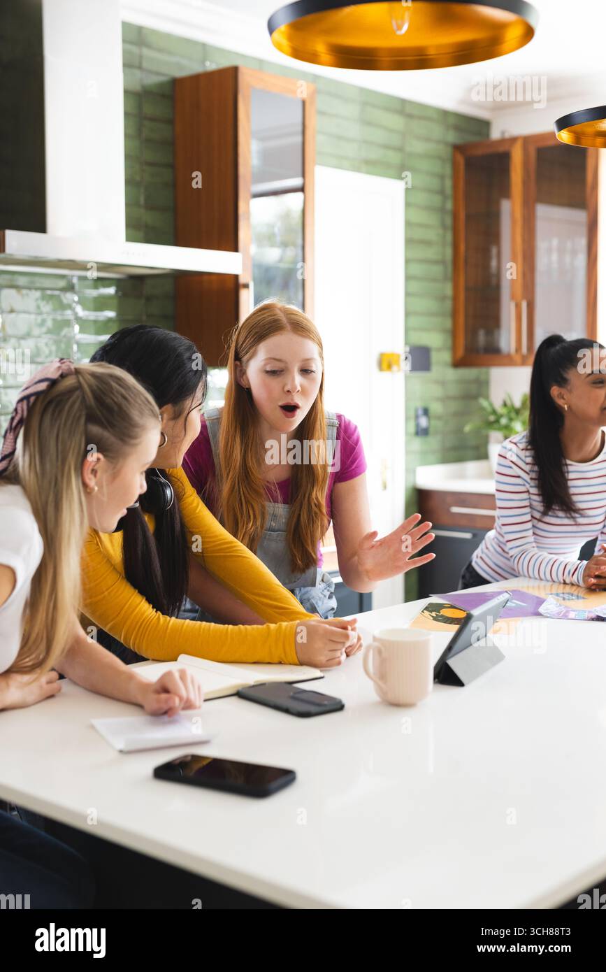 Teenager-Mädchen diskutieren zuhause mit Tablets und Notebooks über Projekte Stockfoto