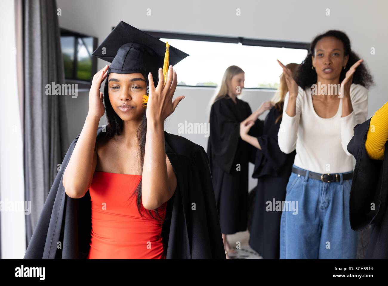 Schulabgänger feiern akademische Leistungen, passen die Kappen freudig an Stockfoto