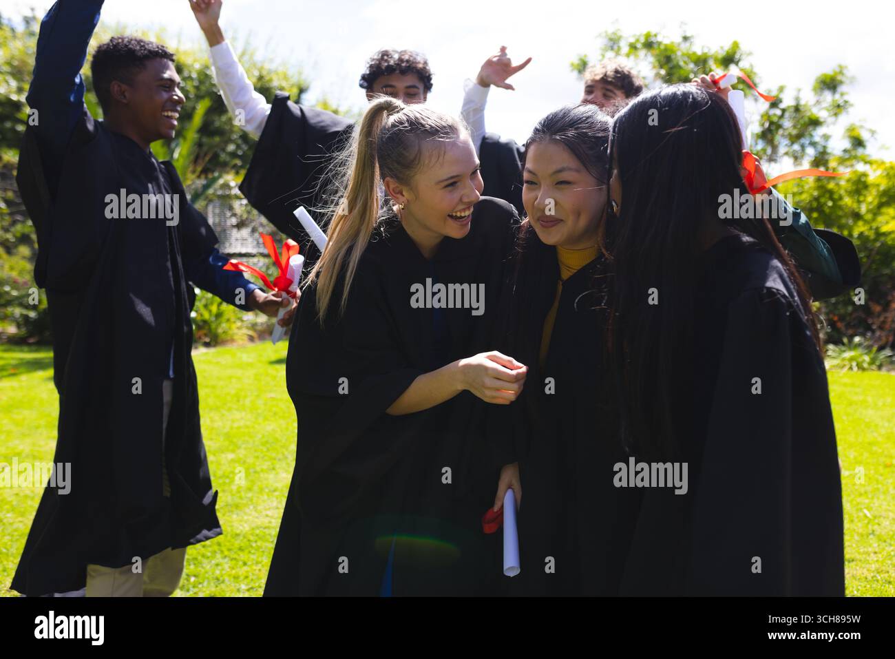 Studenten, die im Freien feiern, lächeln und in Begeisterung Diplome halten Stockfoto