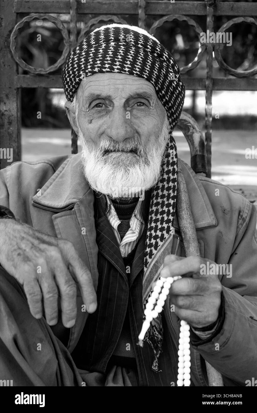 Ein älterer Kurdenmann in traditioneller Kleidung sitzt auf einer Straße in Erbil und zeigt das tägliche Leben und die kurdische Kultur. Stockfoto