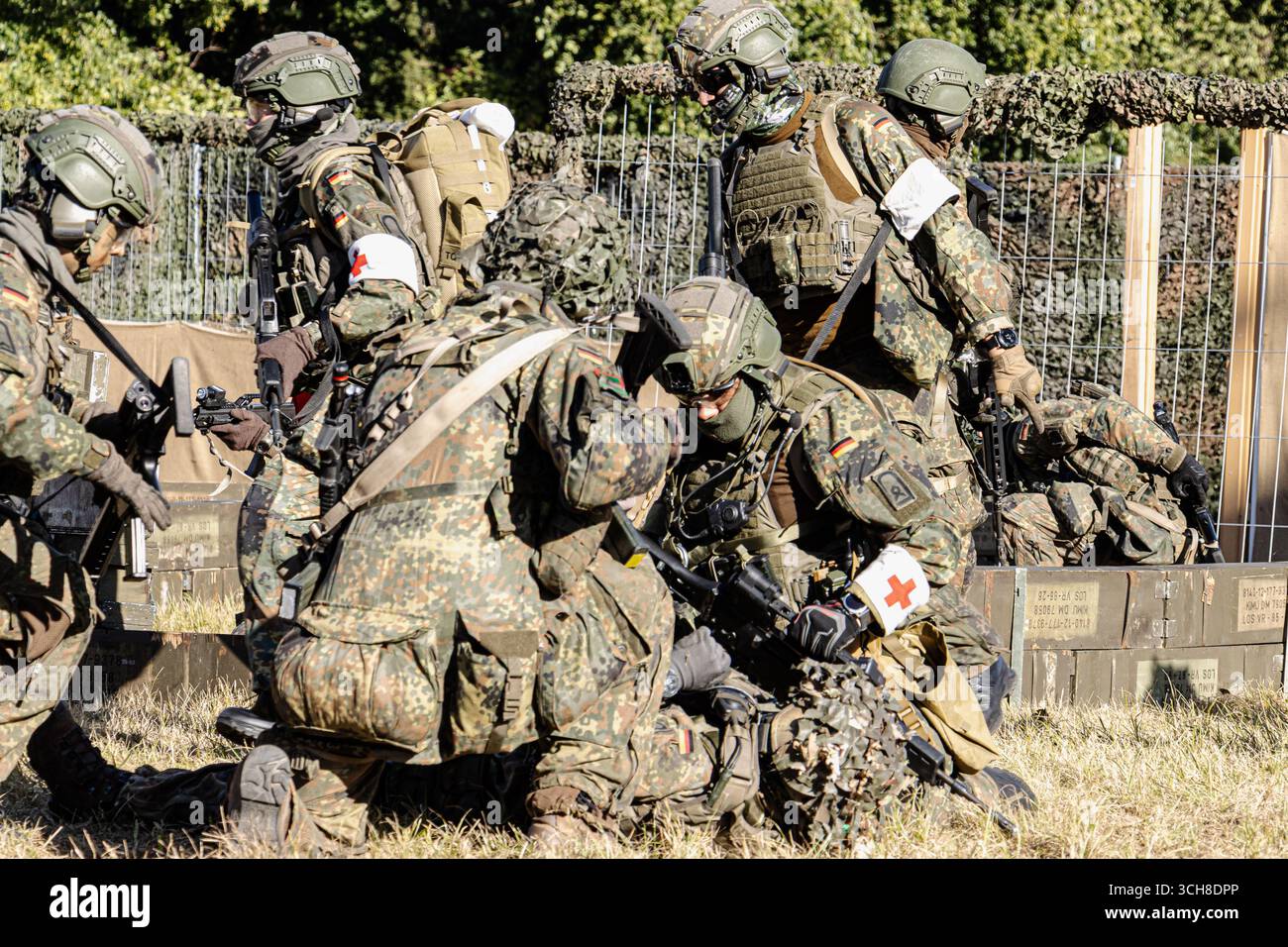 Fallschirmjäger der Bundeswehr in Kampfausrüstung nehmen an einer Trainingsübung teil, bei der ein verwundeter Soldat unterstützt und evakuiert wird Stockfoto