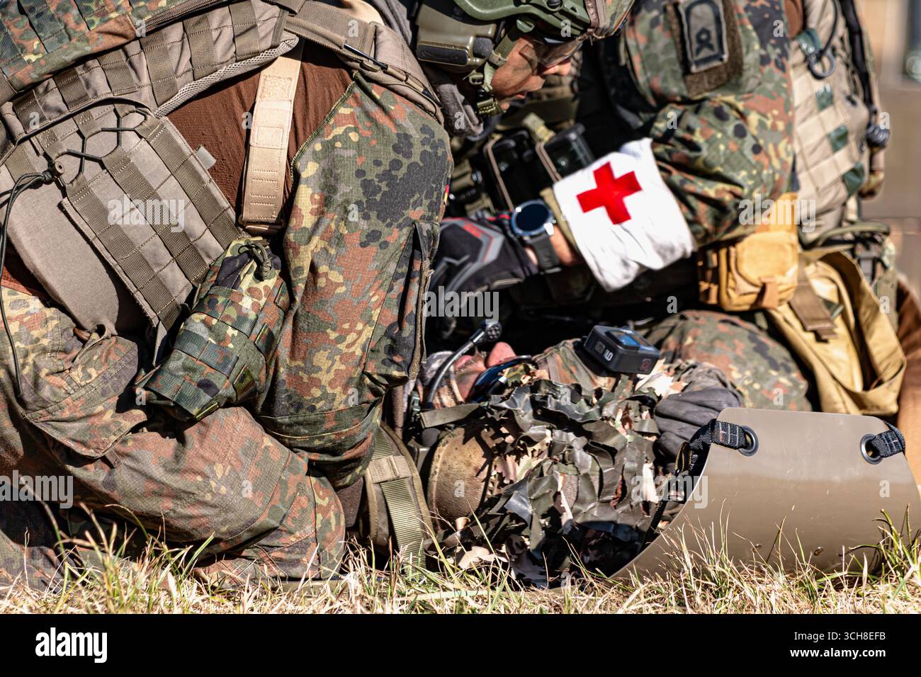 Fallschirmjäger der Bundeswehr in Kampfausrüstung nehmen an einer Trainingsübung teil, bei der ein verwundeter Soldat unterstützt und evakuiert wird Stockfoto