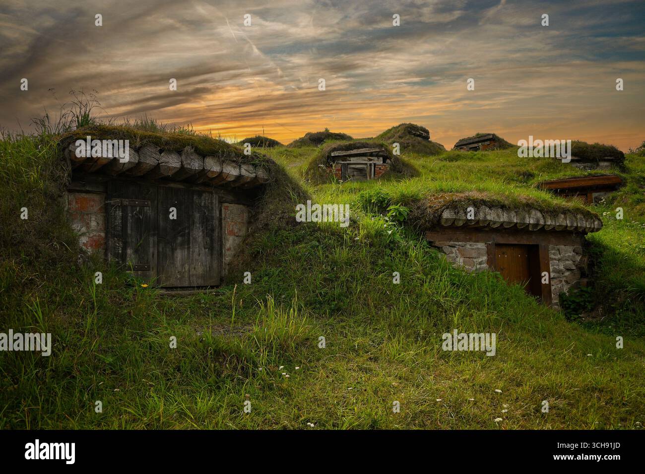 Traditionelle Weinkeller bilden kleine Hügel, die bei einem wunderschönen Sonnenuntergang mit Gras bedeckt sind. Stockfoto