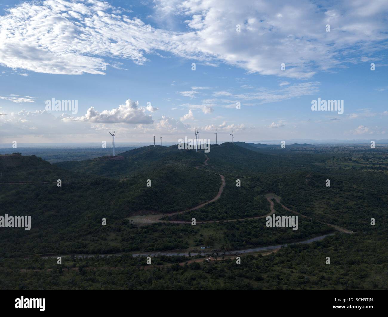 Aus der Vogelperspektive stehen Windturbinen hoch über den hügeligen grünen Hügeln unter einem weiten Himmel und schaffen einen beeindruckenden Kontrast zwischen Natur und Technik, Hosur, Karnataka, Indien. Stockfoto