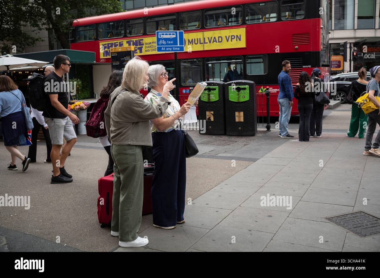 Touristen mittleren Alters sehen sich eine Straßenkarte der Gegend an, während sie an einer Straßenecke im Zentrum von London, England, Großbritannien, halten Stockfoto