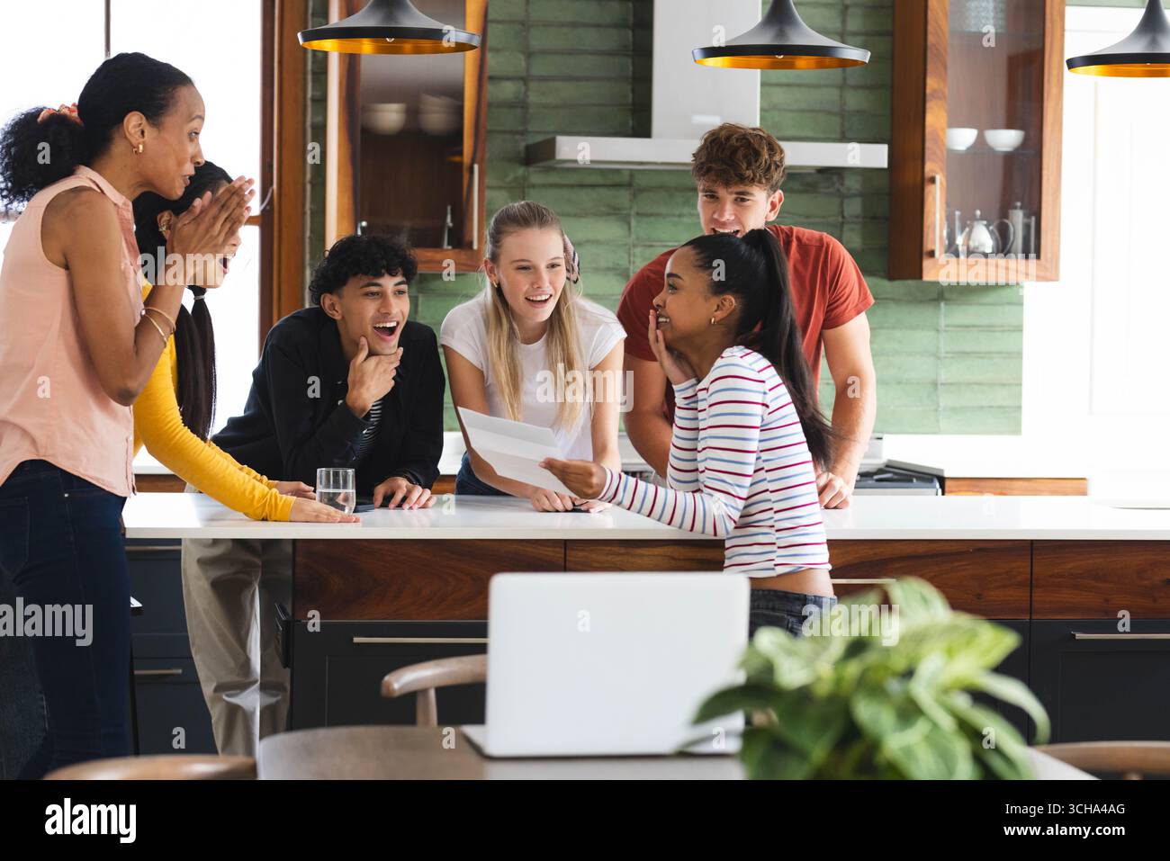 Verschiedene Teenager feiern in der Küche, teilen spannende Neuigkeiten und genießen die Zweisamkeit zu Hause. Feier, Glück, Freundschaft, Bindung, Party, Yo Stockfoto