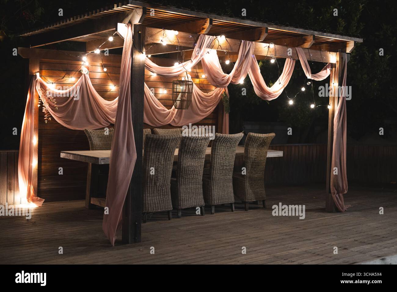 Essbereich im Freien, wunderschön dekoriert mit drapierten Stoffen und Lichterketten. Dekoration, Ambiente, Eleganz, festlich, Veranstaltung, Beleuchtung Stockfoto