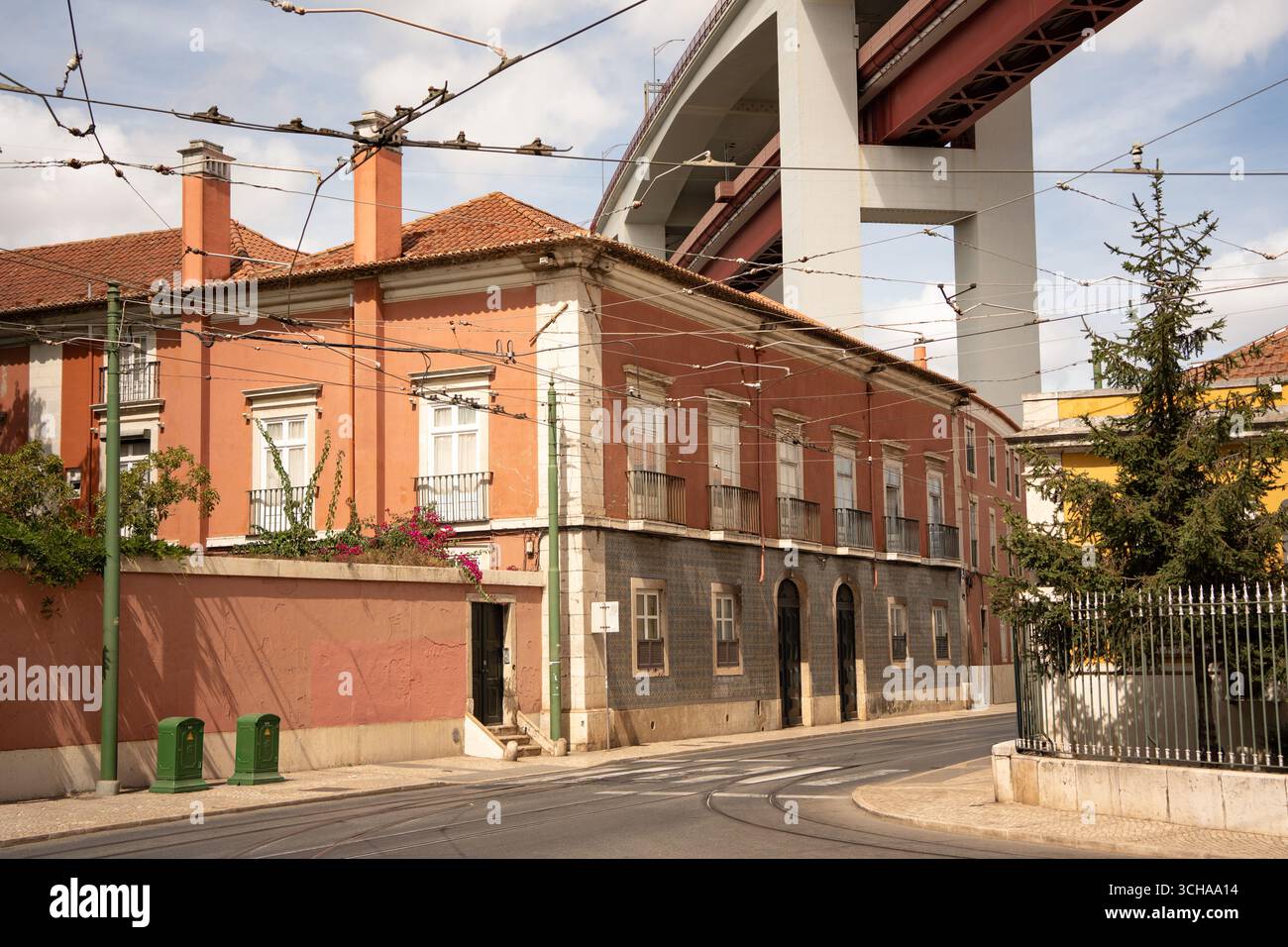 Blick auf die Straße in Lissabons Alcântara, wo die Brücke 25 de Abril in starkem Kontrast zu den charmanten alten Gebäuden steht und die Gegend geprägt hat. Stockfoto