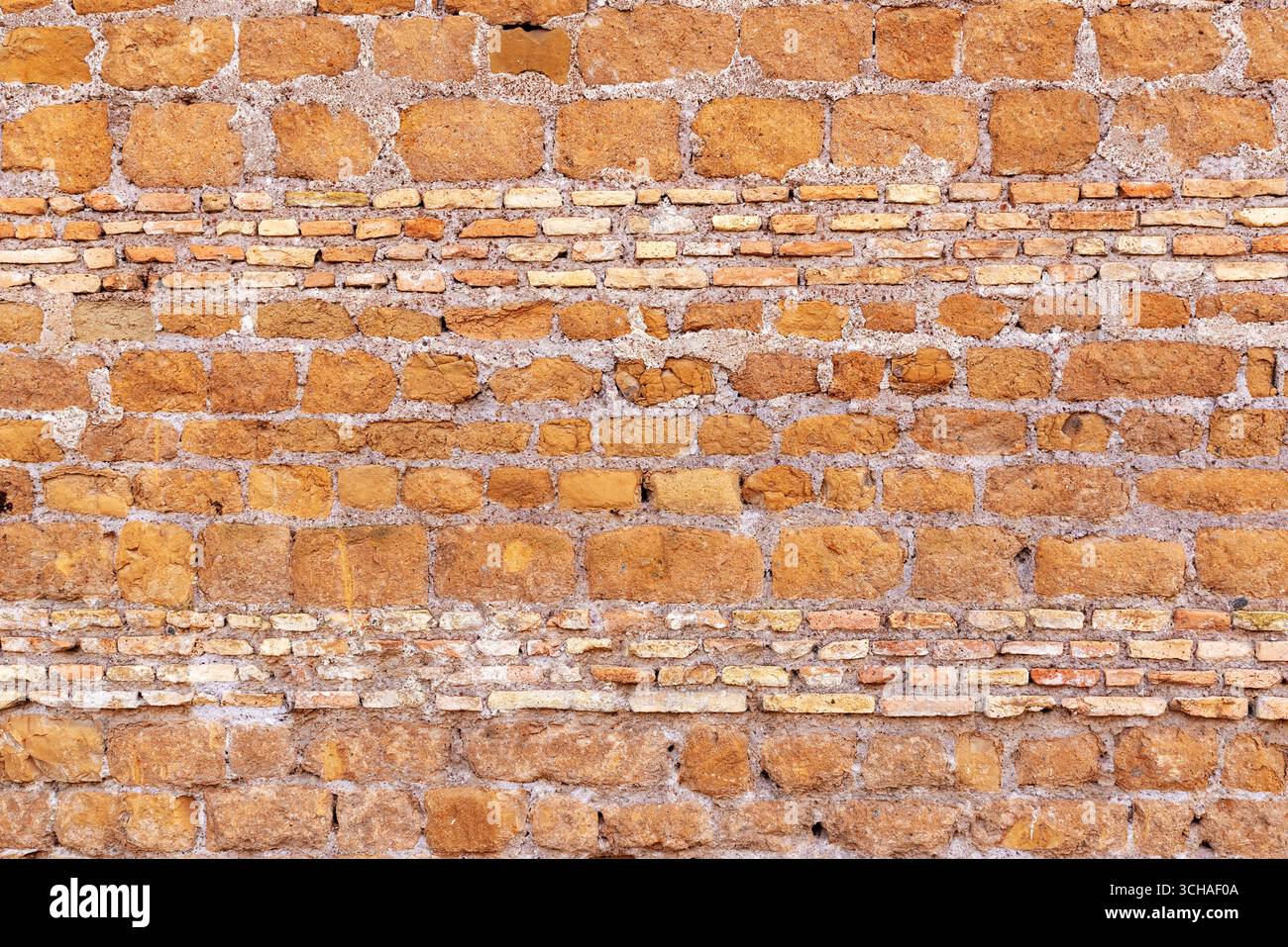 Abgenutzte Ziegeloberfläche mit unregelmäßigen Mustern und Erdtönen, geeignet für Design und architektonische Textur Stockfoto