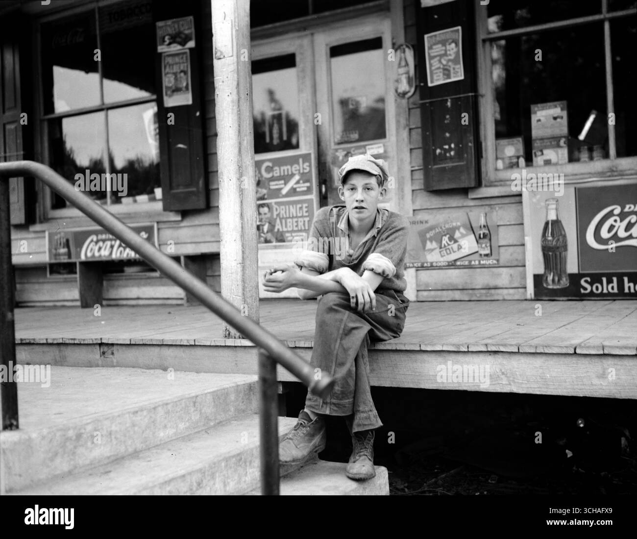 Junge auf der Veranda eines Gemischtwarenladens mit Werbeschildern, Roseland, Virginia." April 1938. Straßenfoto von John Vachon, U.S. Farm Security Administration, US-Regierung Stockfoto Junge auf der Veranda eines Gemischtwarenladens mit Werbeschildern, Roseland, Virginia." April 1938. Straßenfoto von John Vachon, U.S. Farm Security Administration, US-Regierung Stockfoto