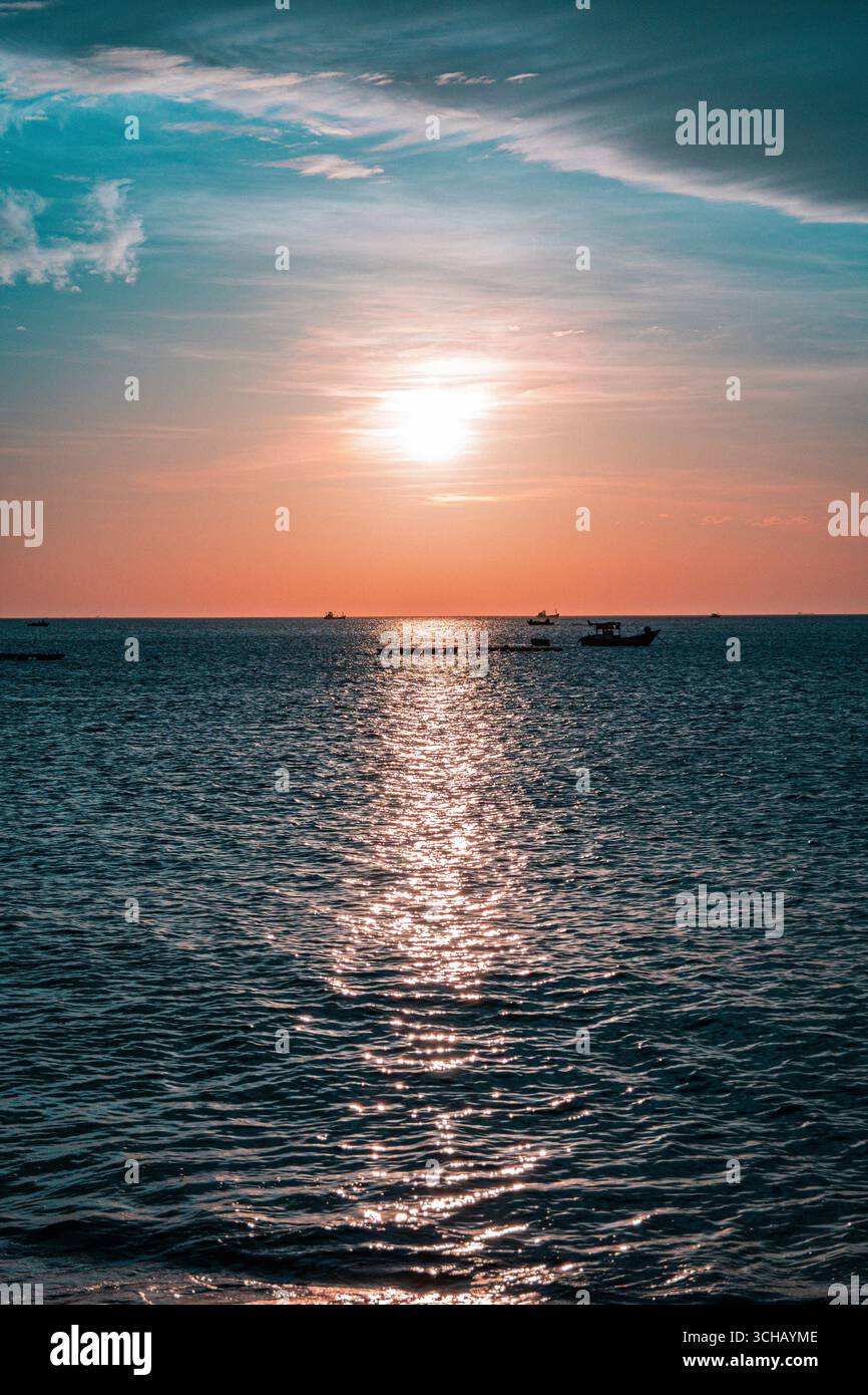 Sonnenuntergang über dem ruhigen Meer mit Fischerbooten, die sich vor dem glühenden Horizont abzeichnen. Stockfoto Sonnenuntergang über dem ruhigen Meer mit Fischerbooten, die sich vor dem glühenden Horizont abzeichnen. Stockfoto