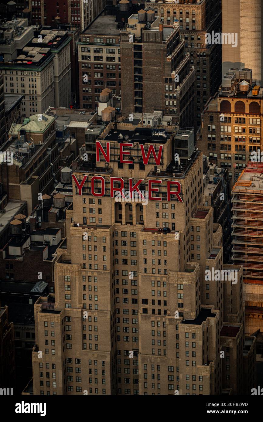 Das ikonische „New Yorker“-Schild krönt das Art déco-Hotel oberhalb von Midtown Manhattan, New York City, das in der Abenddämmerung von einem hohen Blickwinkel aus gesehen wird. Stockfoto