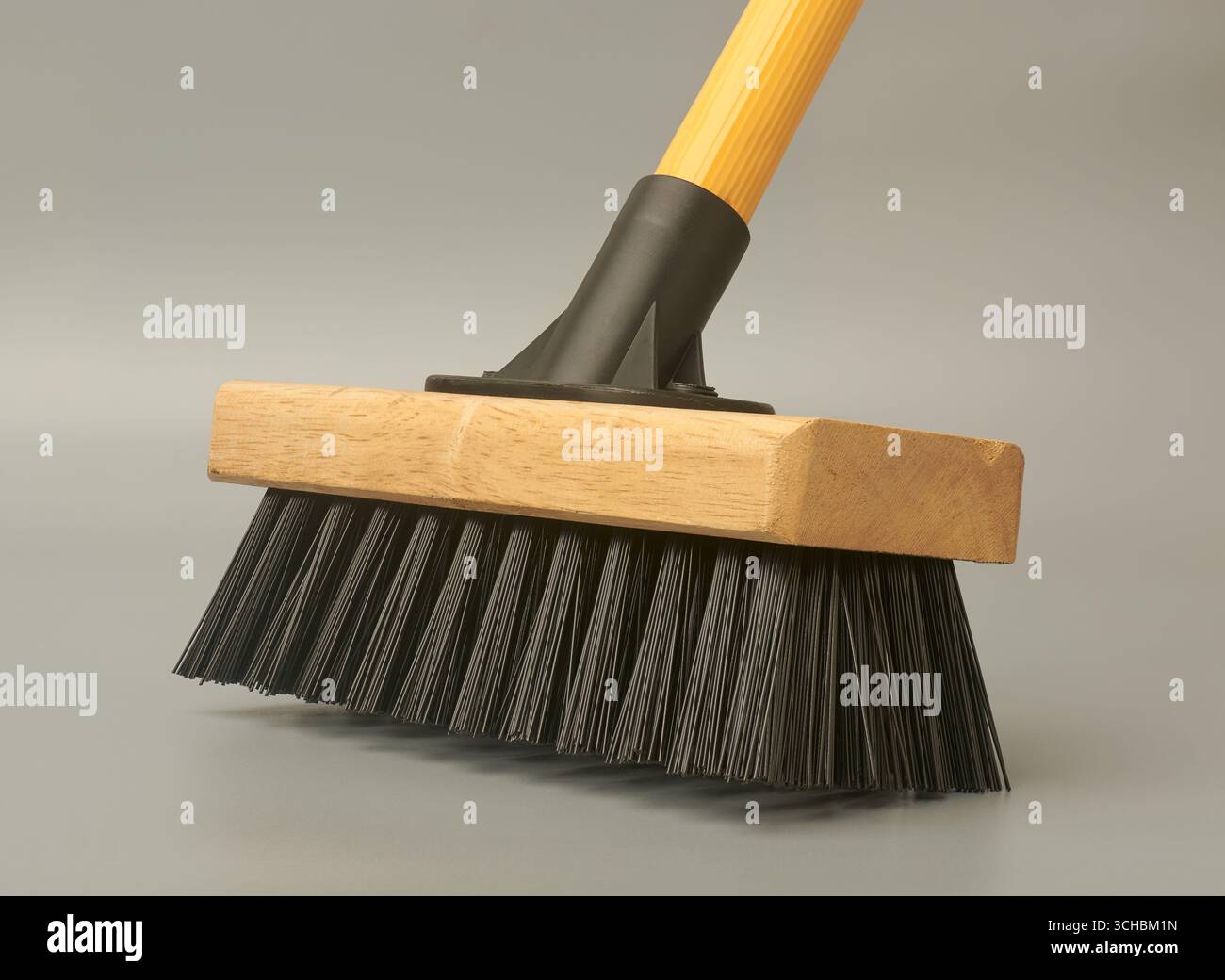 Scheuerbesen oder Deckbürste aus Nahaufnahme mit Holzkopf und schwarzen Borsten isoliertem grauen Hintergrund, Seitenansicht Stockfoto