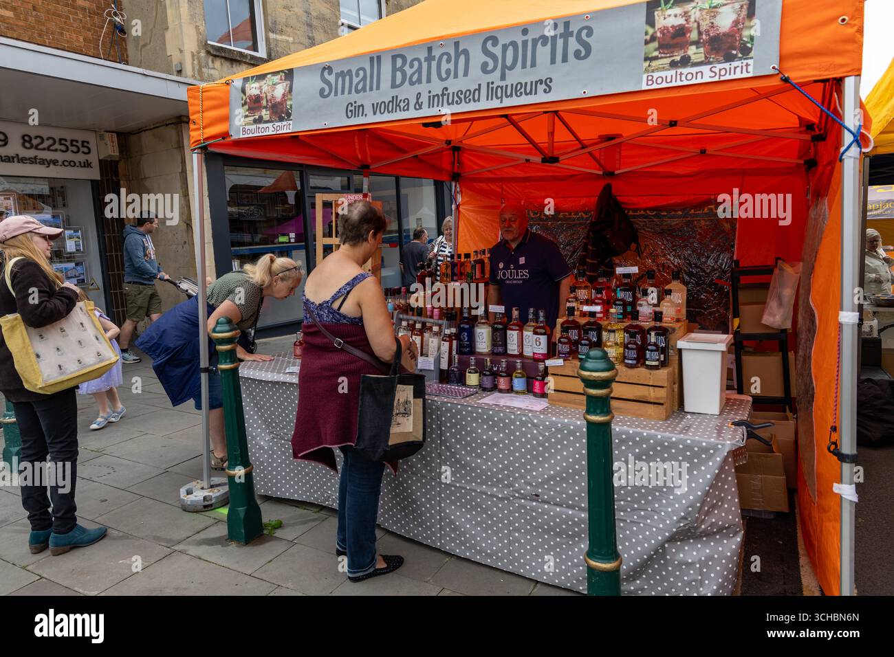 Die Leute erkunden einen Marktstand, der eine Vielzahl kleiner Spirituosen wie Gin, Wodka und infundierte Liköre im Freien verkauft Stockfoto