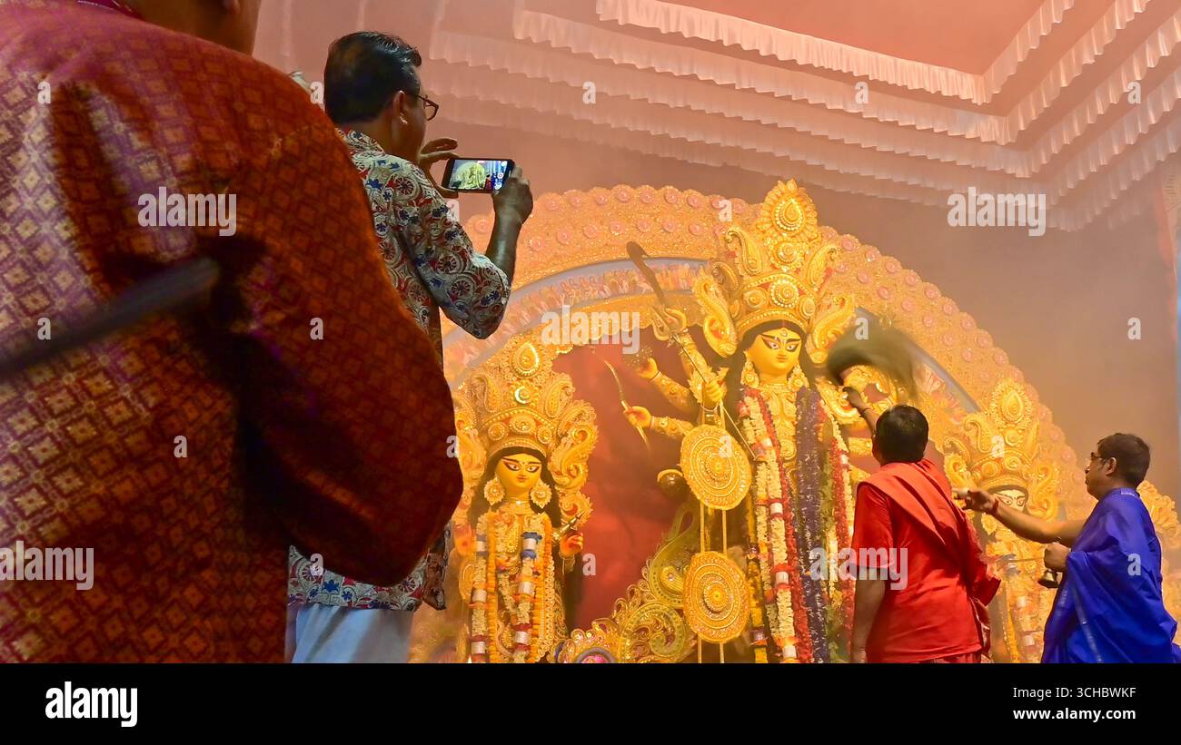Howrah, Westbengalen, Indien -11.10.2024 : ein Anhänger macht Fotos, während die Hindu-Purohten während des Sondhipujo die Göttin Durga anbeten. Stockfoto