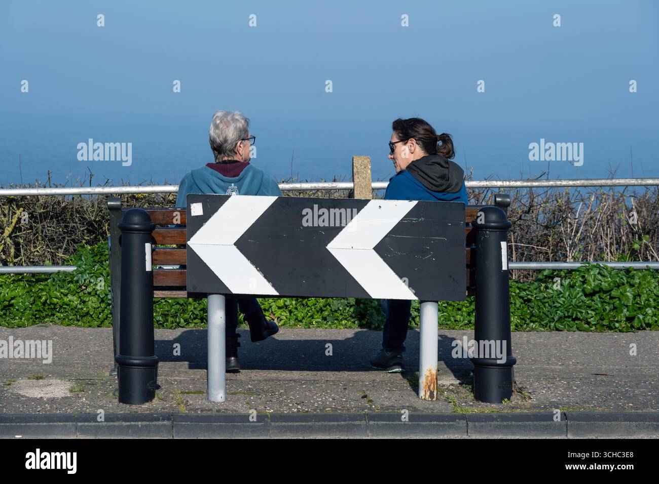 Zwei ältere Freundinnen sitzen auf der Nordsee, overstrand, norfolk, england Stockfoto