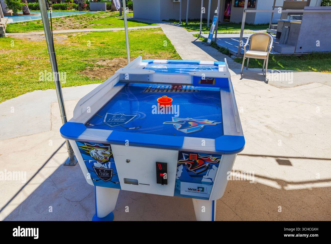 Nahansicht des blauen Air Hockey-Tisches mit orangefarbenem Puck im Freien im sonnigen Resorthintergrund. Kos. Griechenland. Stockfoto