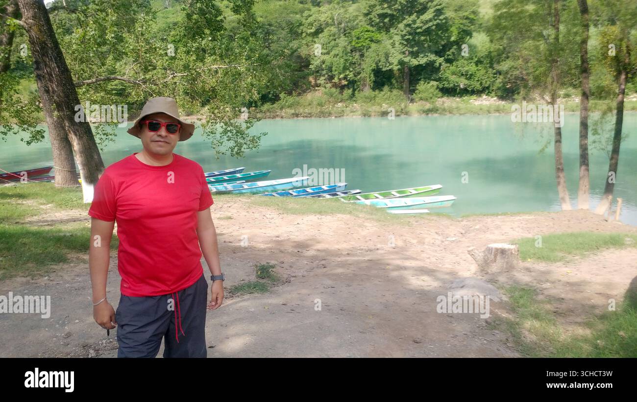 Ein erwachsener Latino-Mann mit Hut, Hemd und roter Brille besucht den Pier des Tamul-Wasserfalls in Huasteca Potosina als Erholung und Entspannung im Urlaub Stockfoto