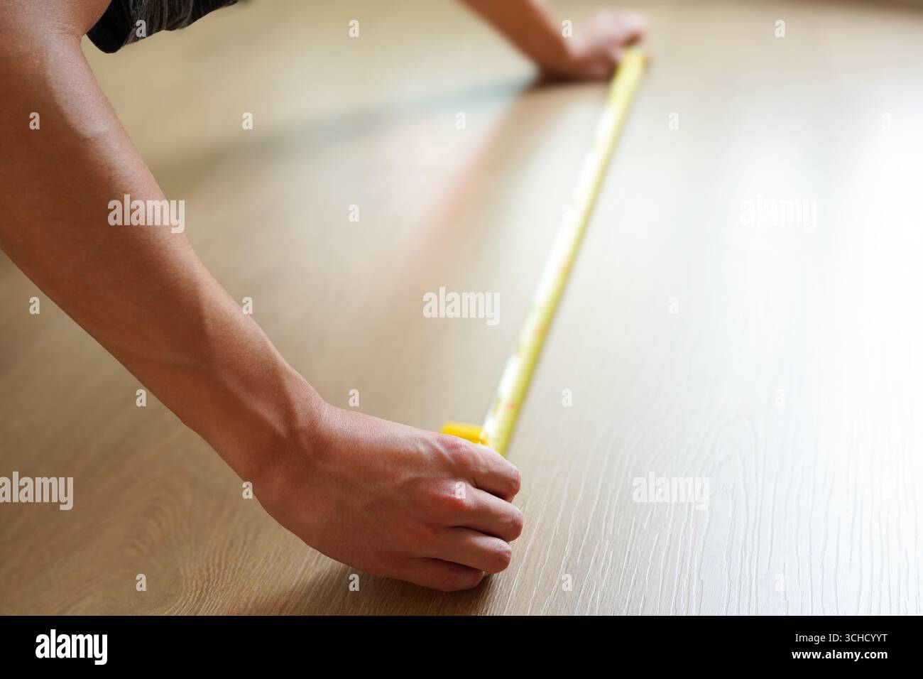 Konzept der Renovierung und des Umzugs, Ein Mann, der den Boden mit einem Maßband misst Stockfoto