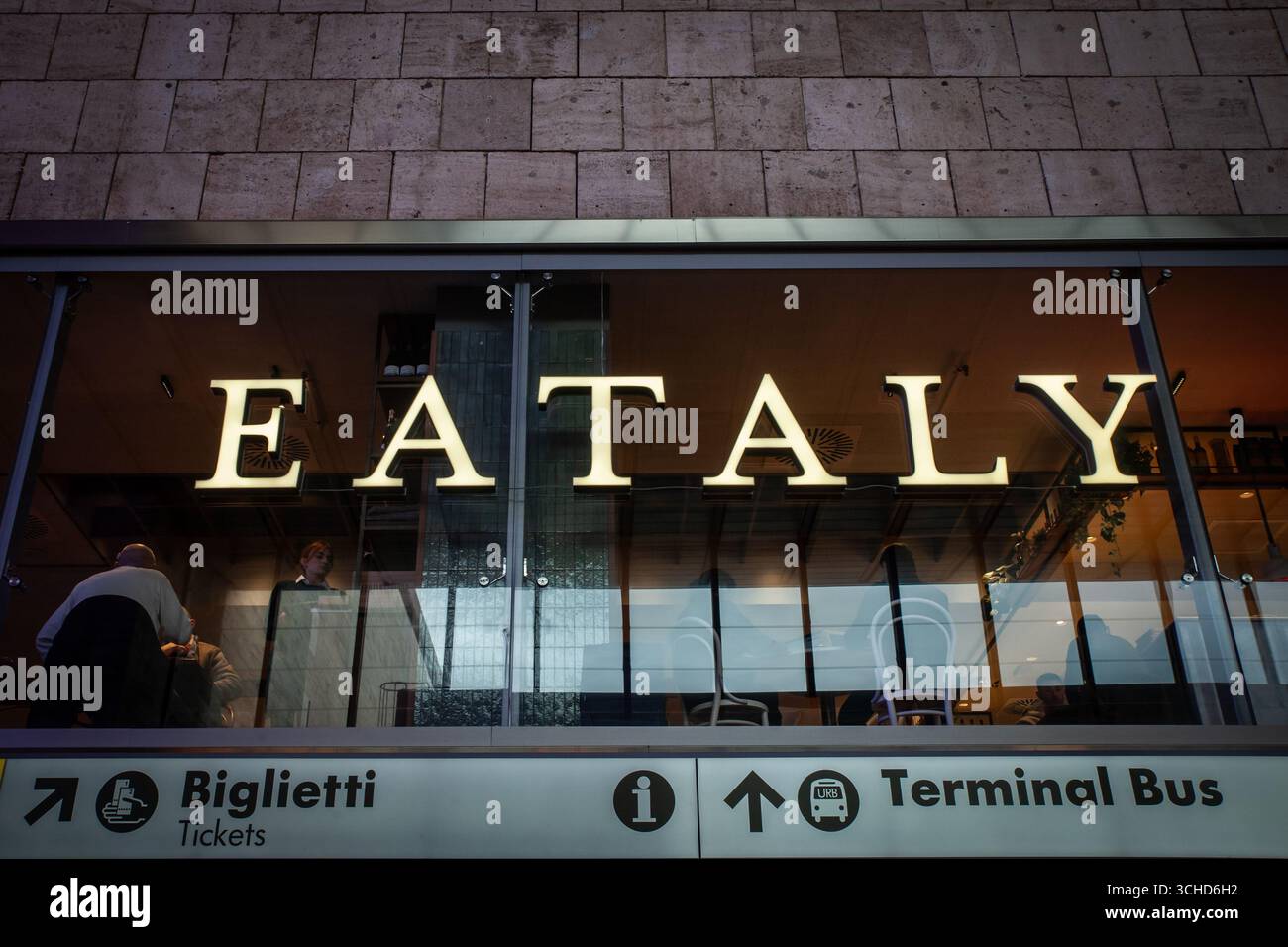 ROM, ITALIEN - 18. JANUAR 2025: Die beleuchtete Eataly-Beschilderung in Rom ist durch Glas zu sehen. Eataly ist eine Kette italienischer Lebensmittelhallen. Stockfoto