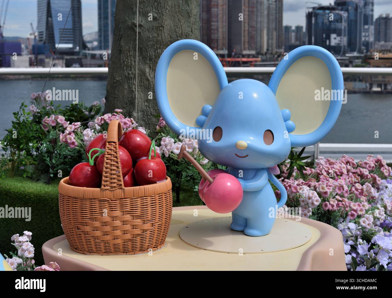 Blaue Maus hält eine Kirsche Stockfoto