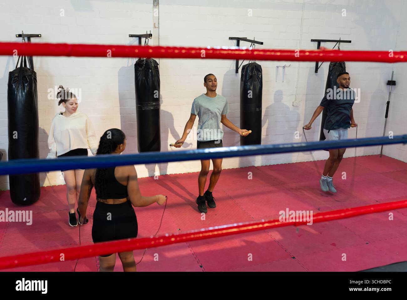 Trainingspartner beim Seilspringen auf Bodenmatten im Turnboxring mit Boxsäcken Stockfoto