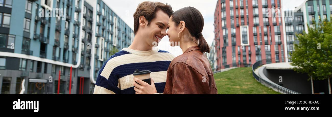 Ein junges Paar genießt freudig Kaffee in einer pulsierenden Stadt voller moderner Gebäude. Stockfoto
