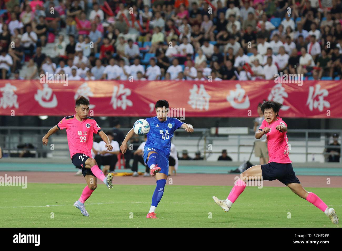 Spieler beider Teams kämpfen während des Spiels heftig. Zhenjiang, China, 31. August 2025. Die neue Runde der Jiangsu City Football League 2025 (Su Chao) begann am Abend des 31. August 2025 in der Stadt Zhenjiang, Provinz Jiangsu. Junge Fans schoben einen riesigen Fußball, um vor dem Spielbeginn eine Aufwärmphase zu machen, was eine lebhafte Atmosphäre auf dem Spielfeld schafft. Quelle: Yang Bo/China News Service/Alamy Live News Stockfoto