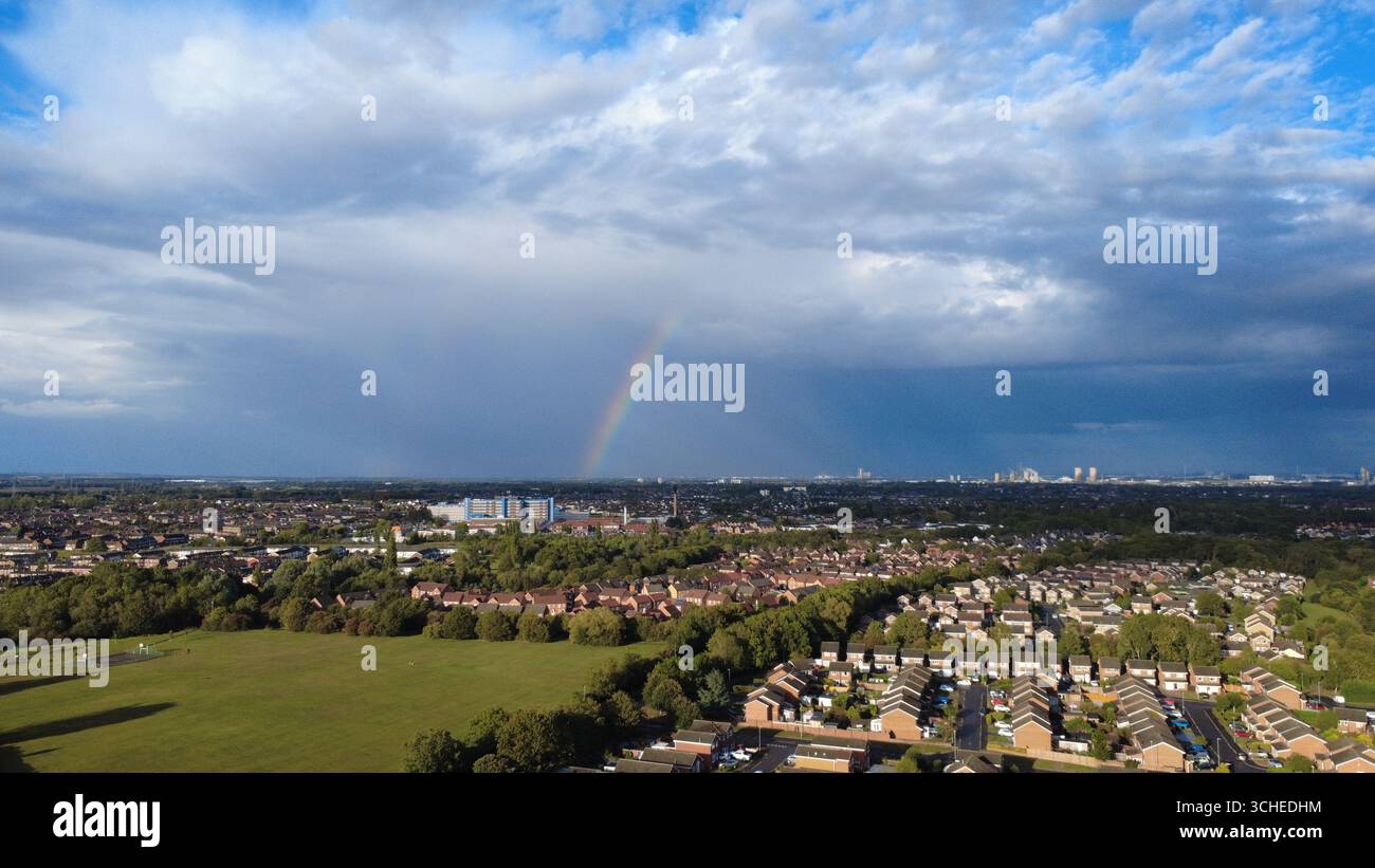 Eine Luftperspektive eines Regenbogens, der die Landschaft unter einem sich verändernden Himmel beleuchtet Stockfoto