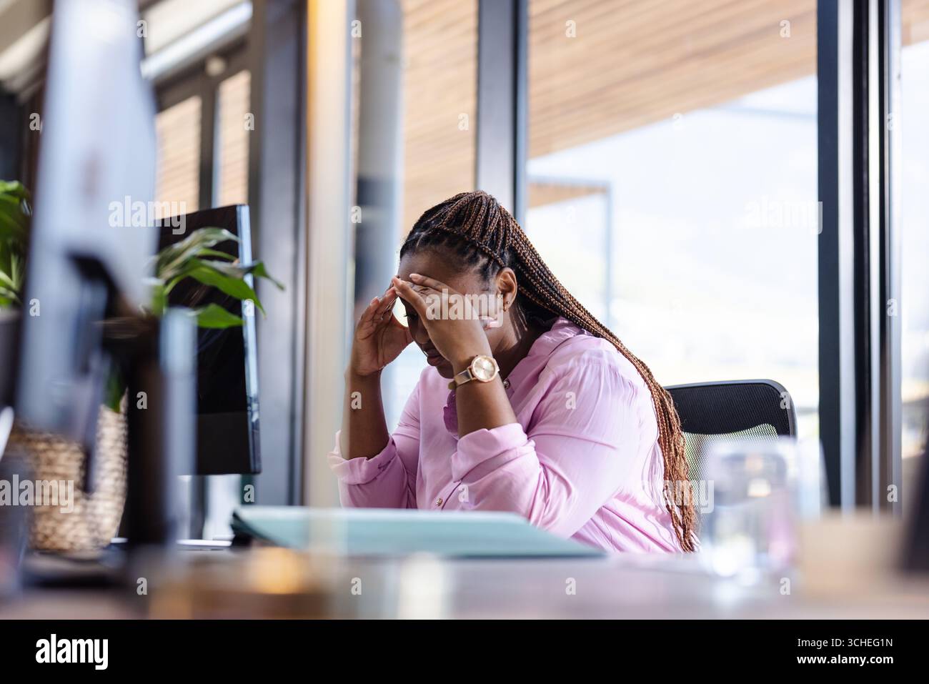 Gestresste Geschäftsfrau im Büro mit Kopf, überfordert von Arbeitsaufgaben Stockfoto