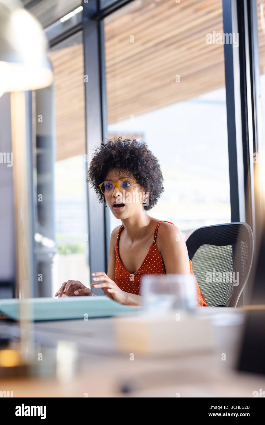 Überraschte Frau im Büro, die auf den Laptop blickte, Brille und Tupfen trug, Kopierraum Stockfoto