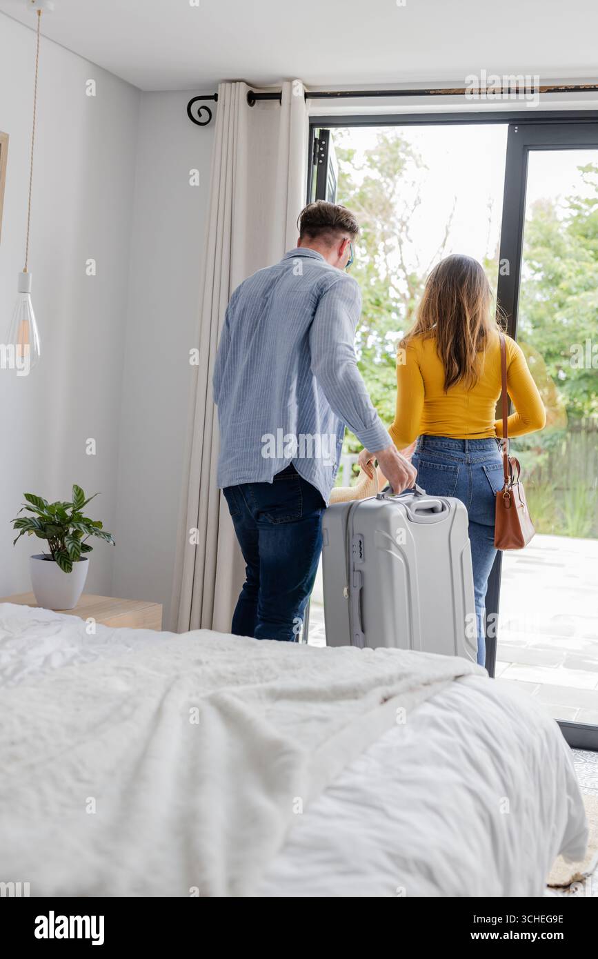 Ein Paar, das mit Koffer zu Hause geht, bereitet sich auf ein gemeinsames Reiseabenteuer vor Stockfoto