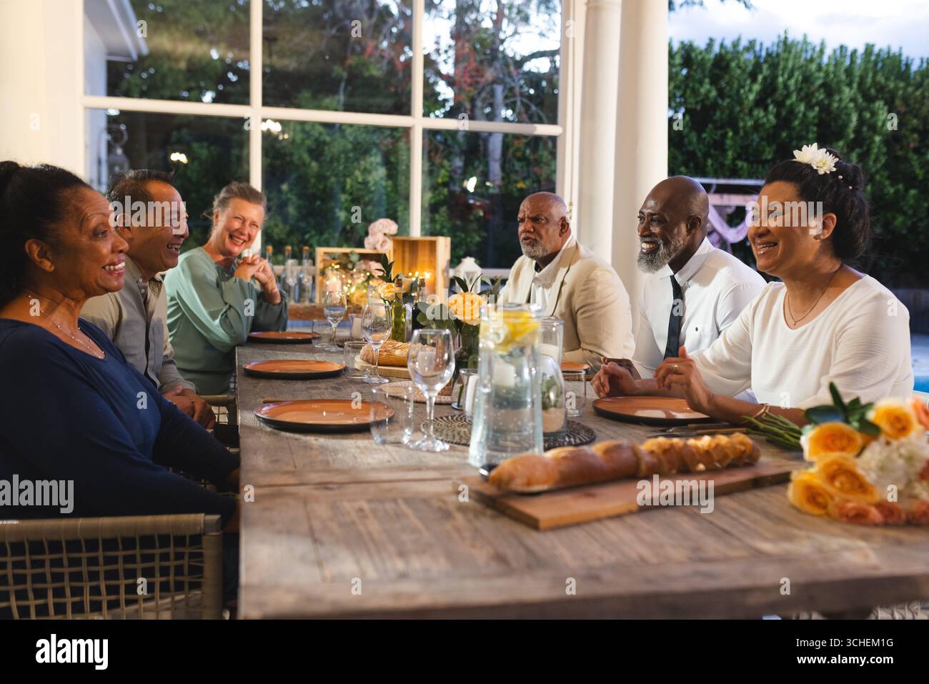 Senioren genießen ein gemeinsames Abendessen, teilen Lachen und Geschichten bei Treffen im Freien Stockfoto