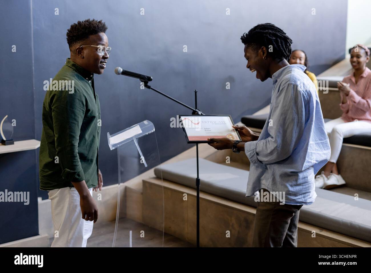 Mann, der auf der Bühne ausgezeichnet wurde, während das Publikum in einem modernen Büroumfeld klatscht Stockfoto