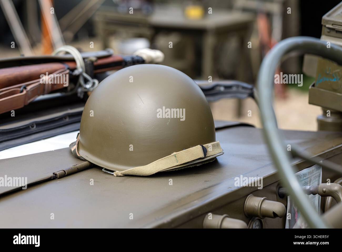 Grüner militärischer Kampfhelm auf einem alten Fahrzeug für die historische Nachstellung des Zweiten Weltkriegs Stockfoto