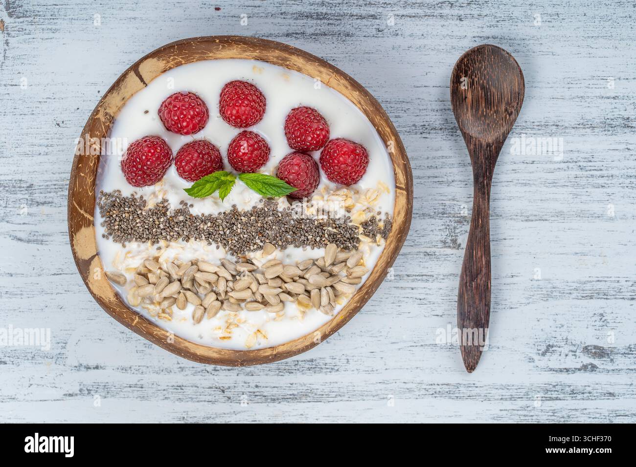 Smoothie in Kokosnuss Schale mit Himbeeren, Haferflocken, Sonnenblumenkerne und Chia Samen zum Frühstück, bis zu schließen. Das Konzept der gesunden Ernährung, superfood. Stockfoto