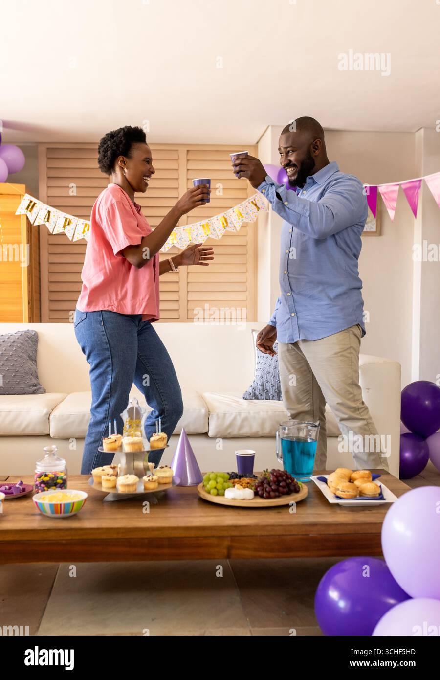 Auf der Party feiern fröhliche Paare zu Hause und trinken während der festlichen Party mit Getränken Stockfoto