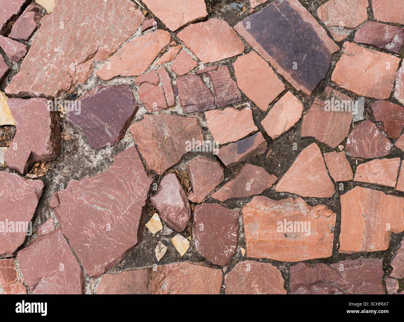 Nahaufnahme einer Kopfsteinpflasterstraße, die mit rotem Marmor (oder Granit) gepflastert ist. Hintergrund. Stockfoto