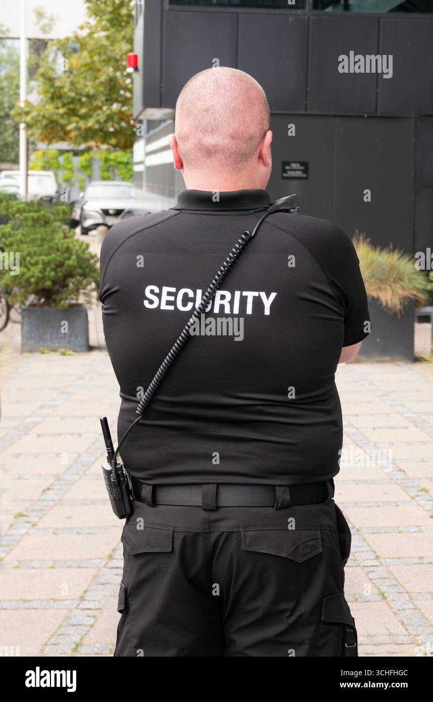 Sicherheitsbeamter von hinten in schwarzer Uniform mit Walkie-Talkie gesehen. Stockfoto